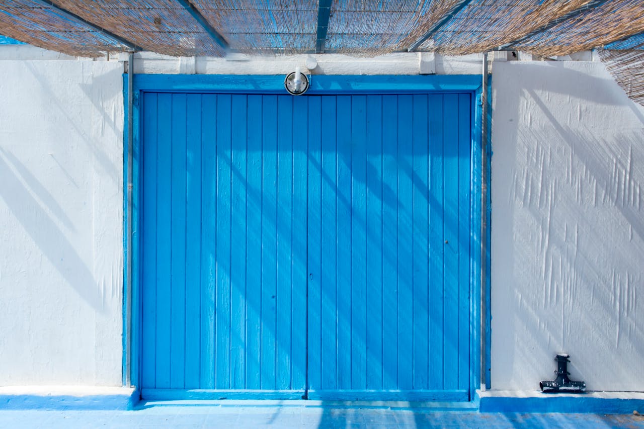 services-04 A vibrant blue wooden door in an urban setting, capturing rustic charm with sunlight and shadows.